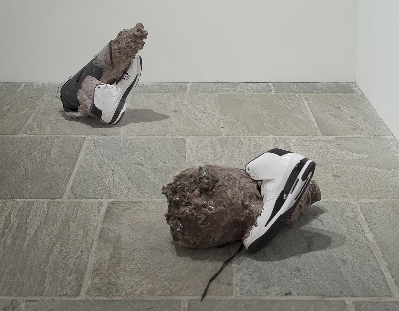 A pair of Air Jordans attached to rocks in a gallery