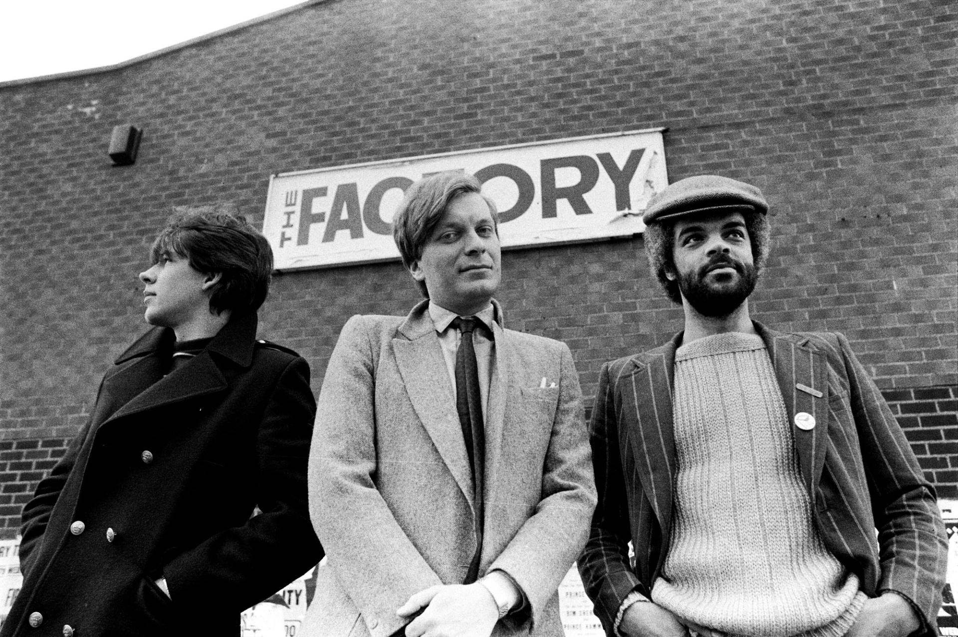 Saville (left) with Tony Wilson (center) and Alan Erasmus (right) outside of The Factory circa 1979. (Photo: Kevin Cummins. Courtesy Getty Images)