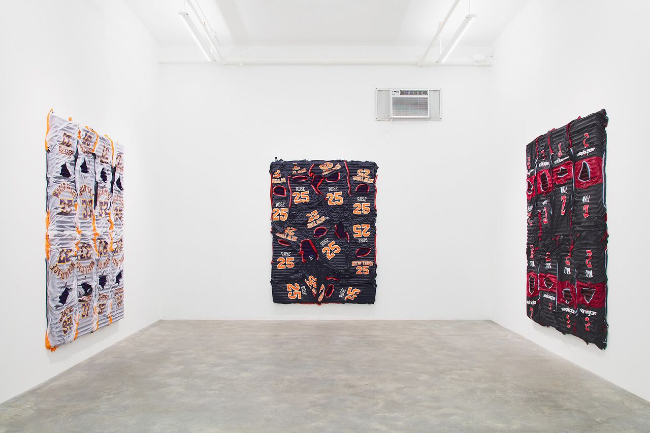 A gallery with three artworks made from sports jerseys hanging on the walls