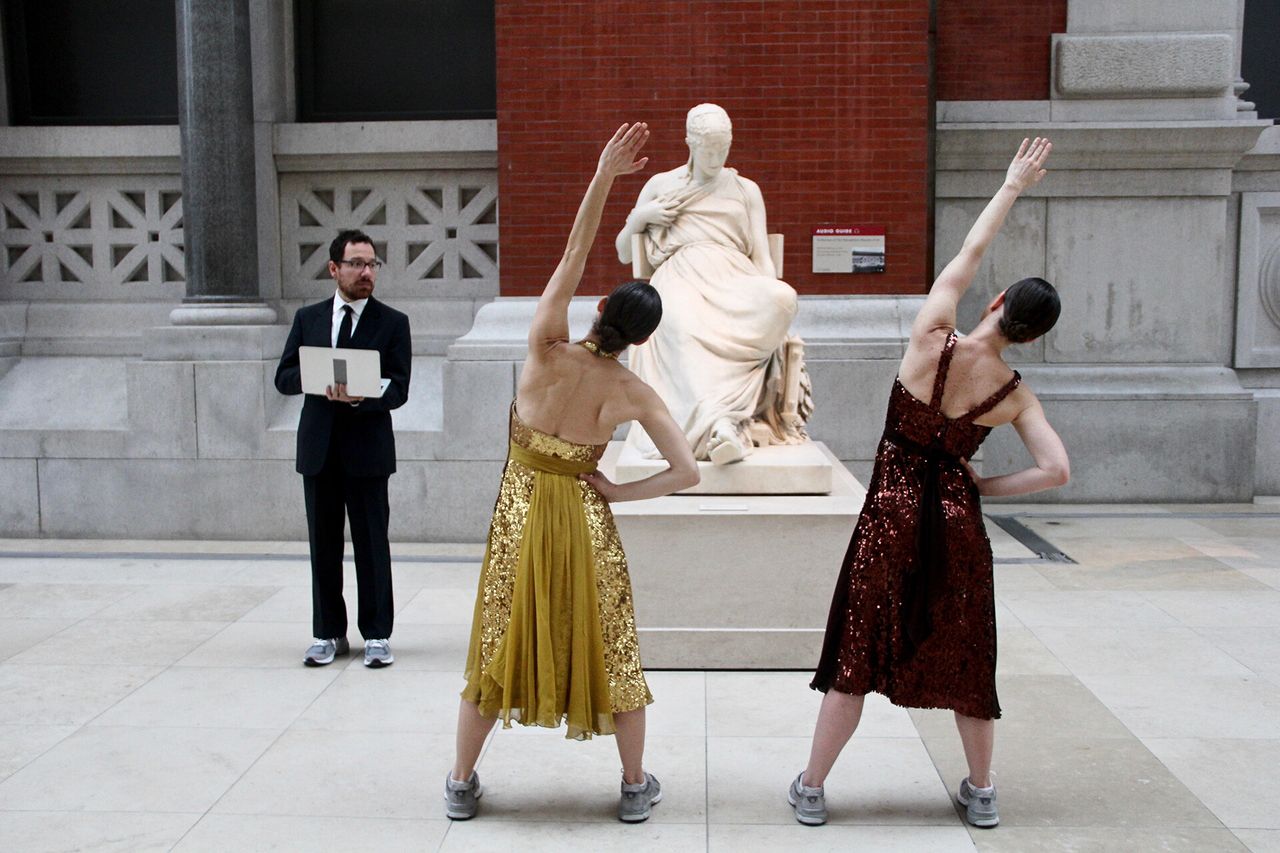 Two dancers in front of a statue