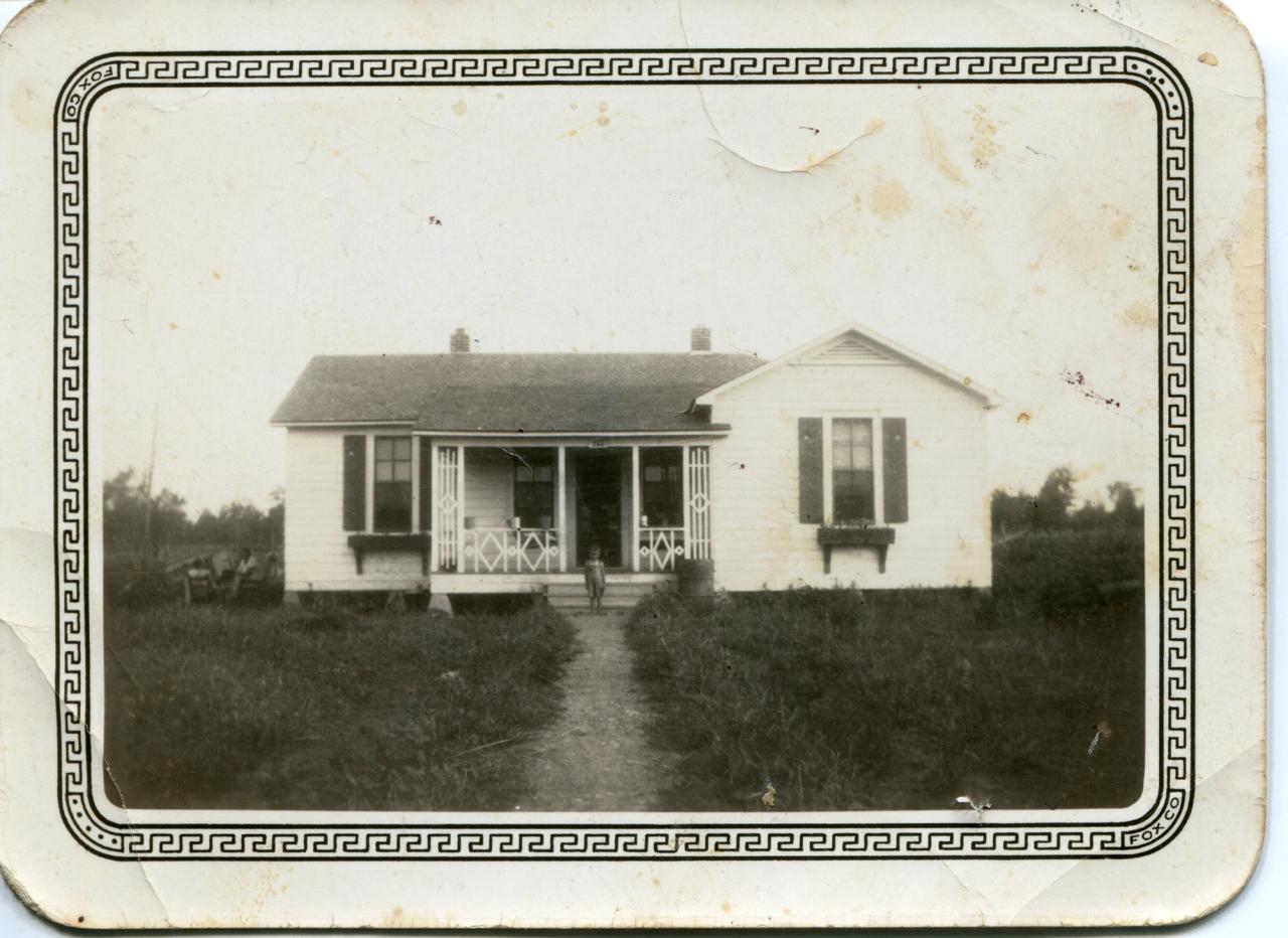 A black and white photo of a white house in the country