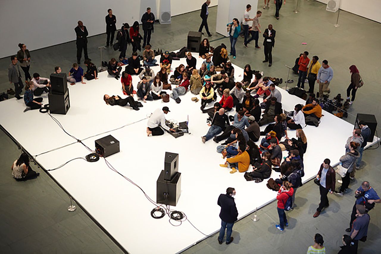 An artist performing at a museum before a crowd