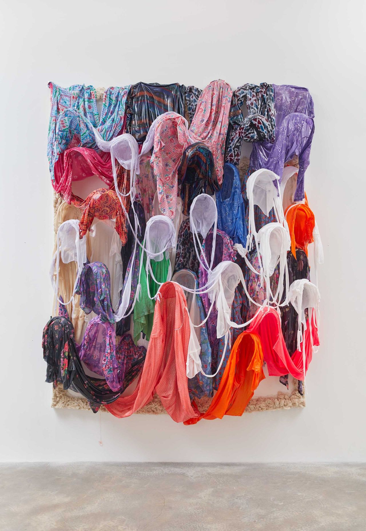An art installation of colored headscarfs hung in a gallery