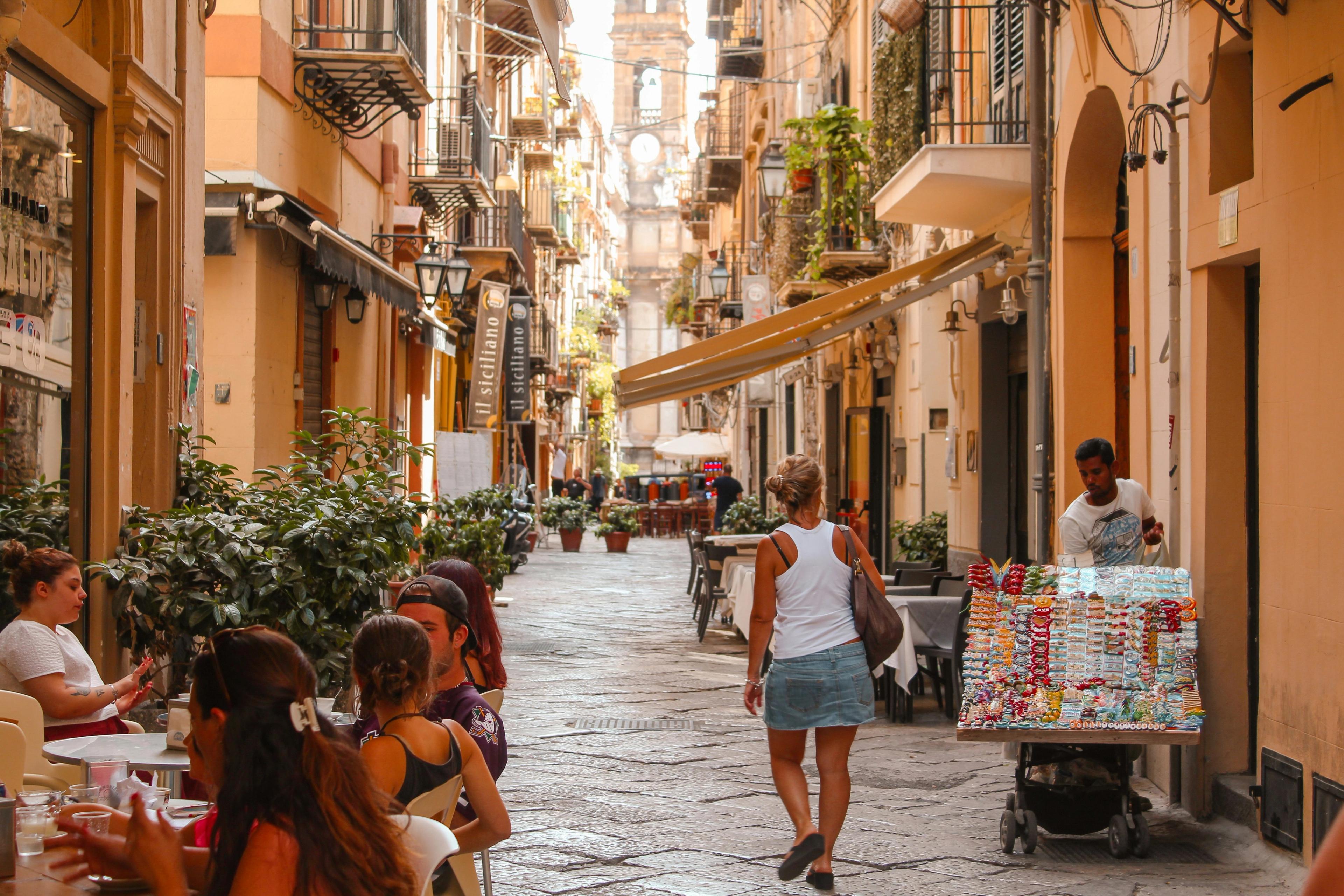 a woman is walking down a narrow street in a city .