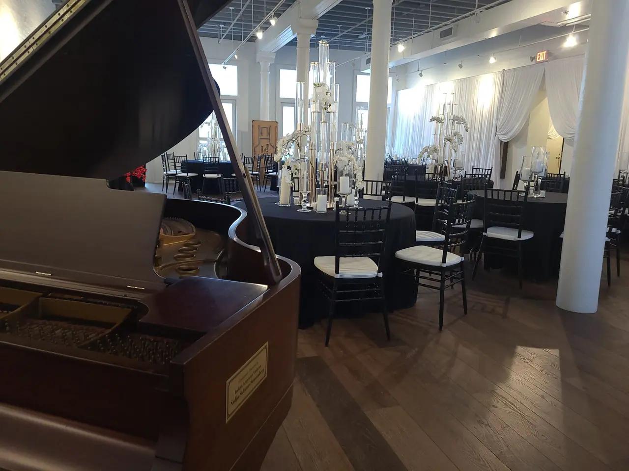 a grand piano is sitting in the middle of a large room with tables and chairs.