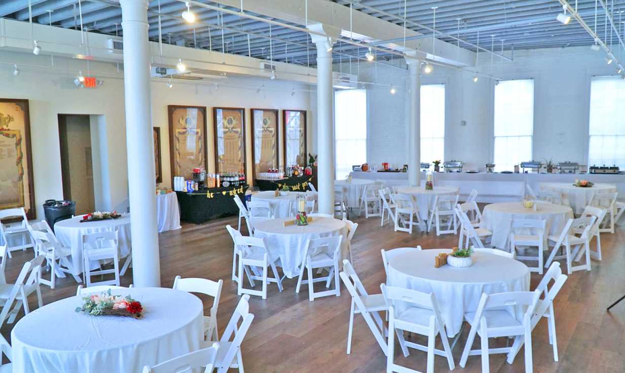a large room with tables and chairs set up for a wedding reception .