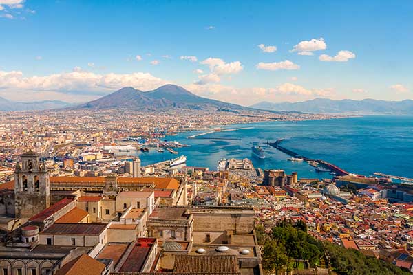 Panoramic view of Naples, Italy, with Mount Vesuvius looming over the Bay of Naples.