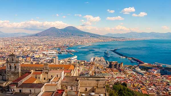 Panoramic view of Naples, Italy, with Mount Vesuvius looming over the Bay of Naples.