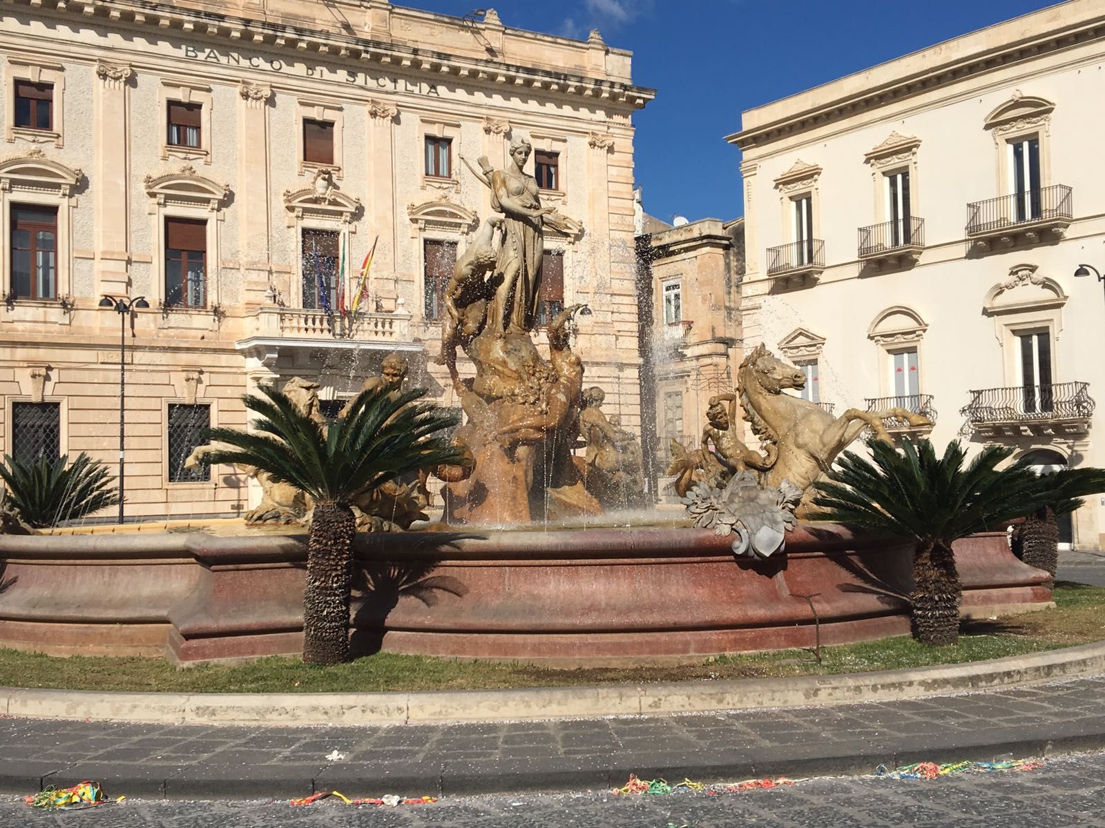 a fountain with a statue of a man on a horse in front of a building .