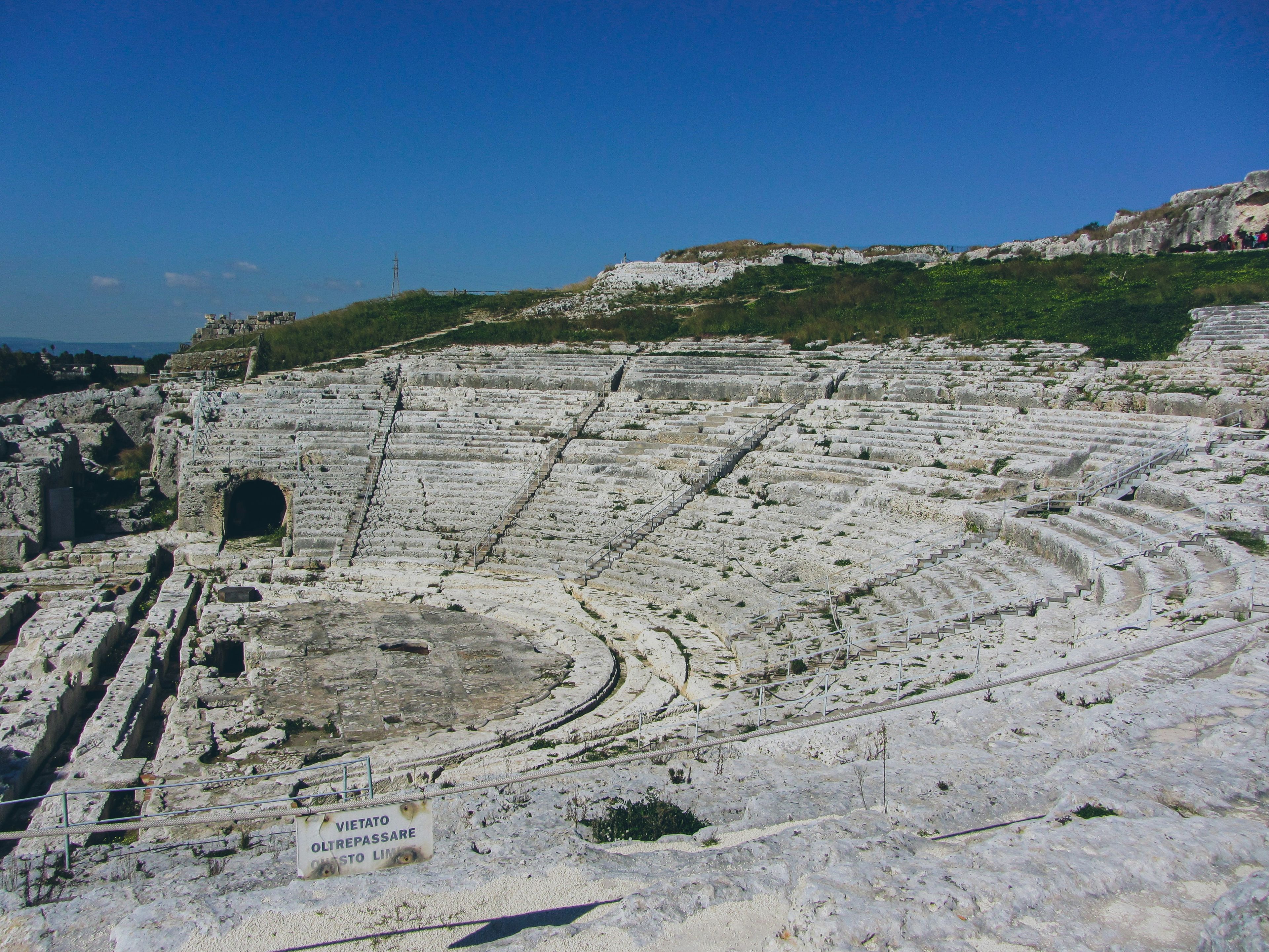 a large white amphitheater is sitting on top of a hill .