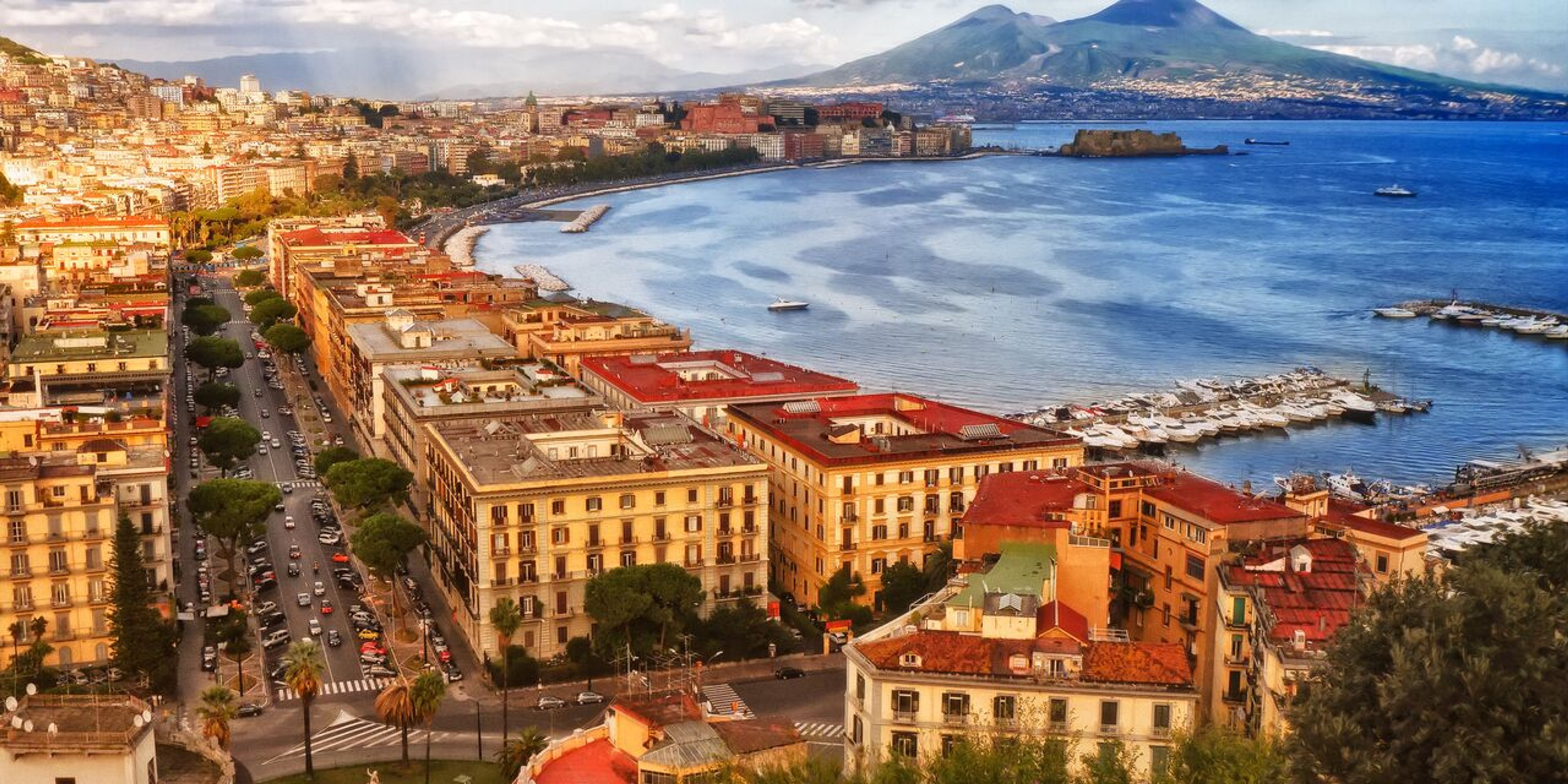 an aerial view of a city next to a body of water with a mountain in the background .