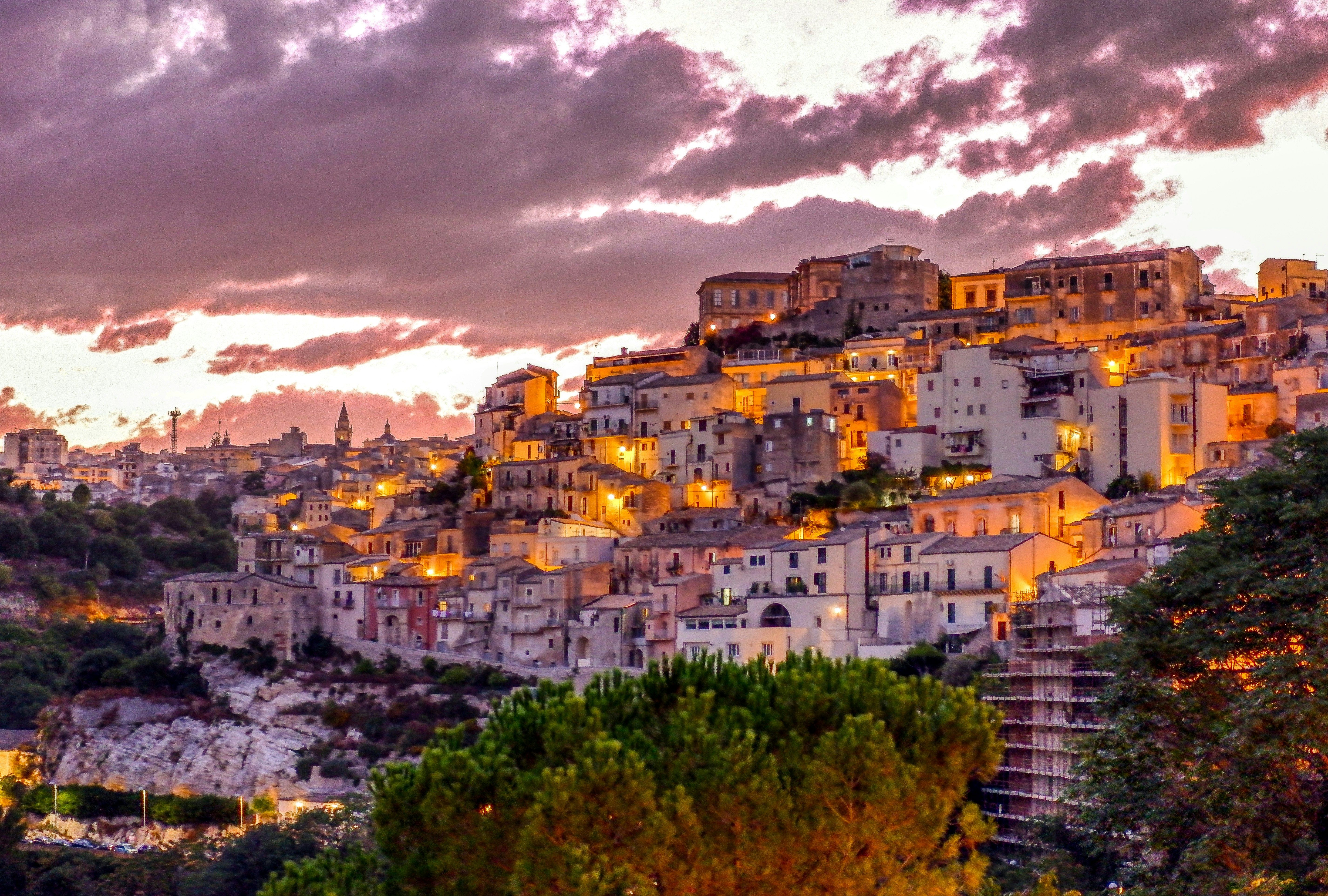 a small town is sitting on top of a hill at sunset .