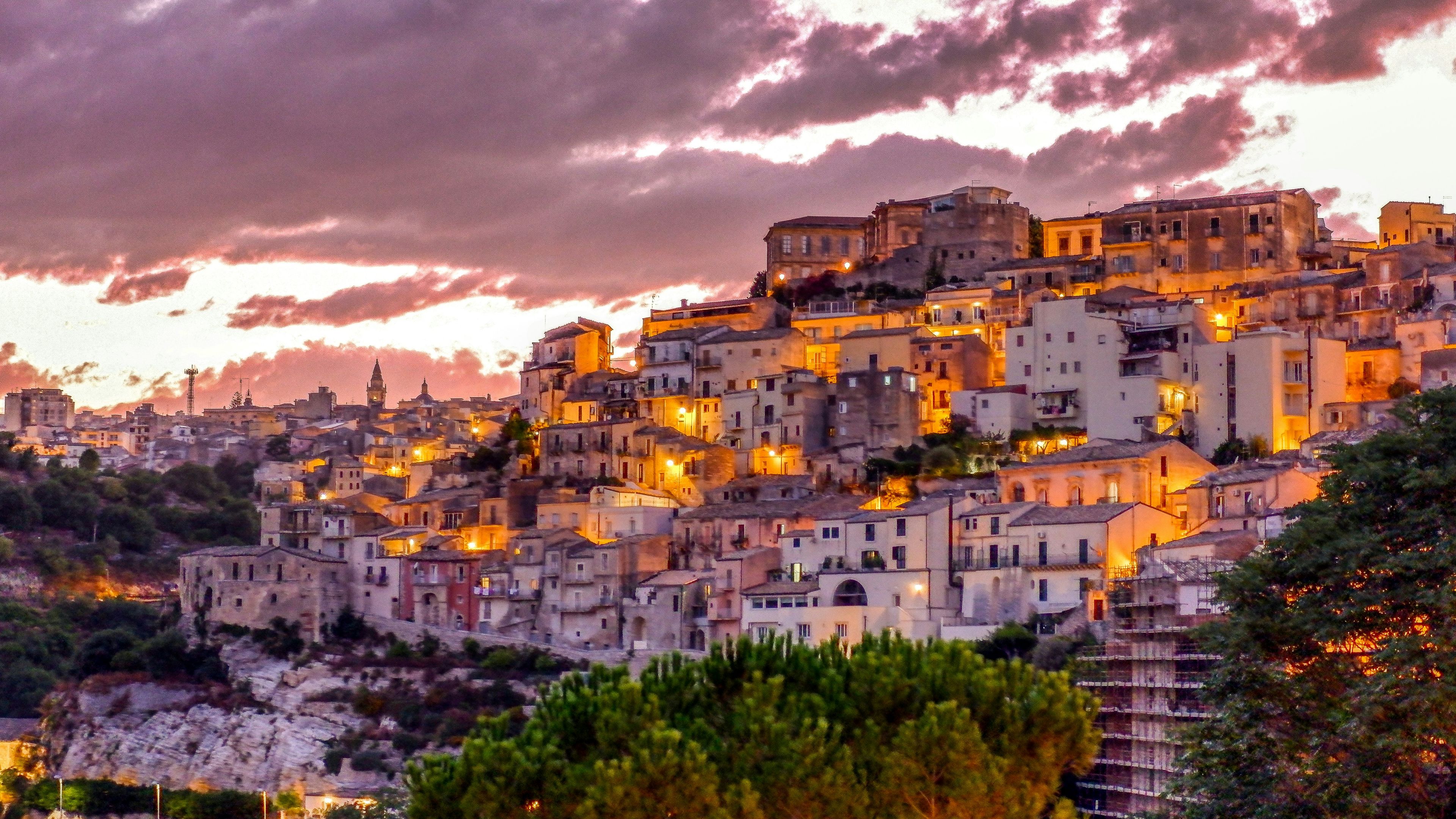 a small town is sitting on top of a hill at sunset .
