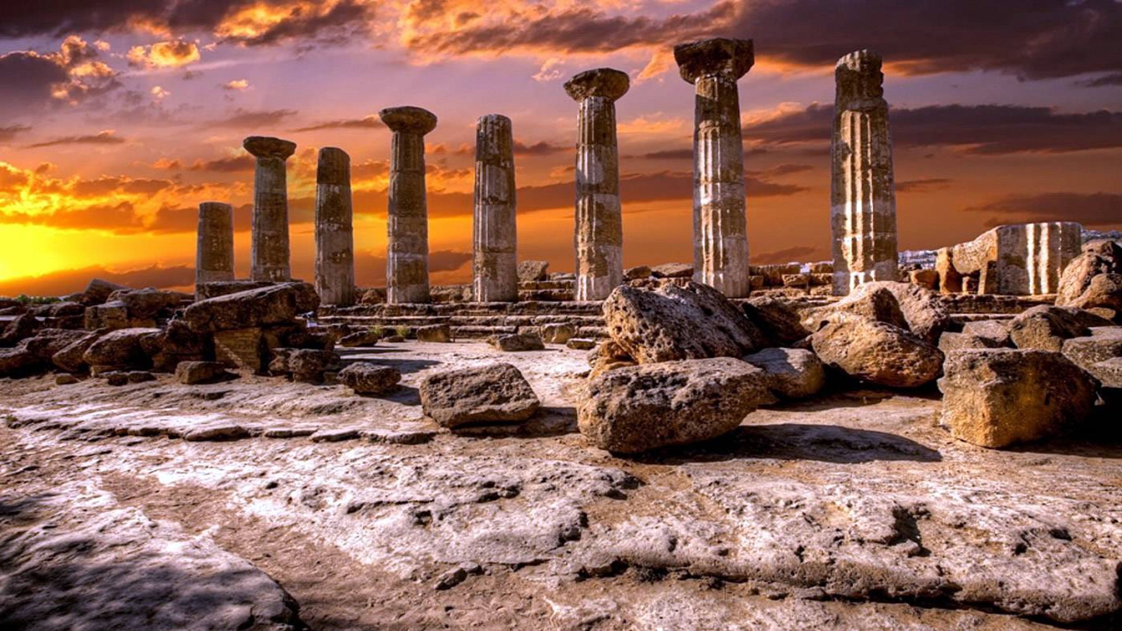 the ruins of an ancient greek temple at sunset .