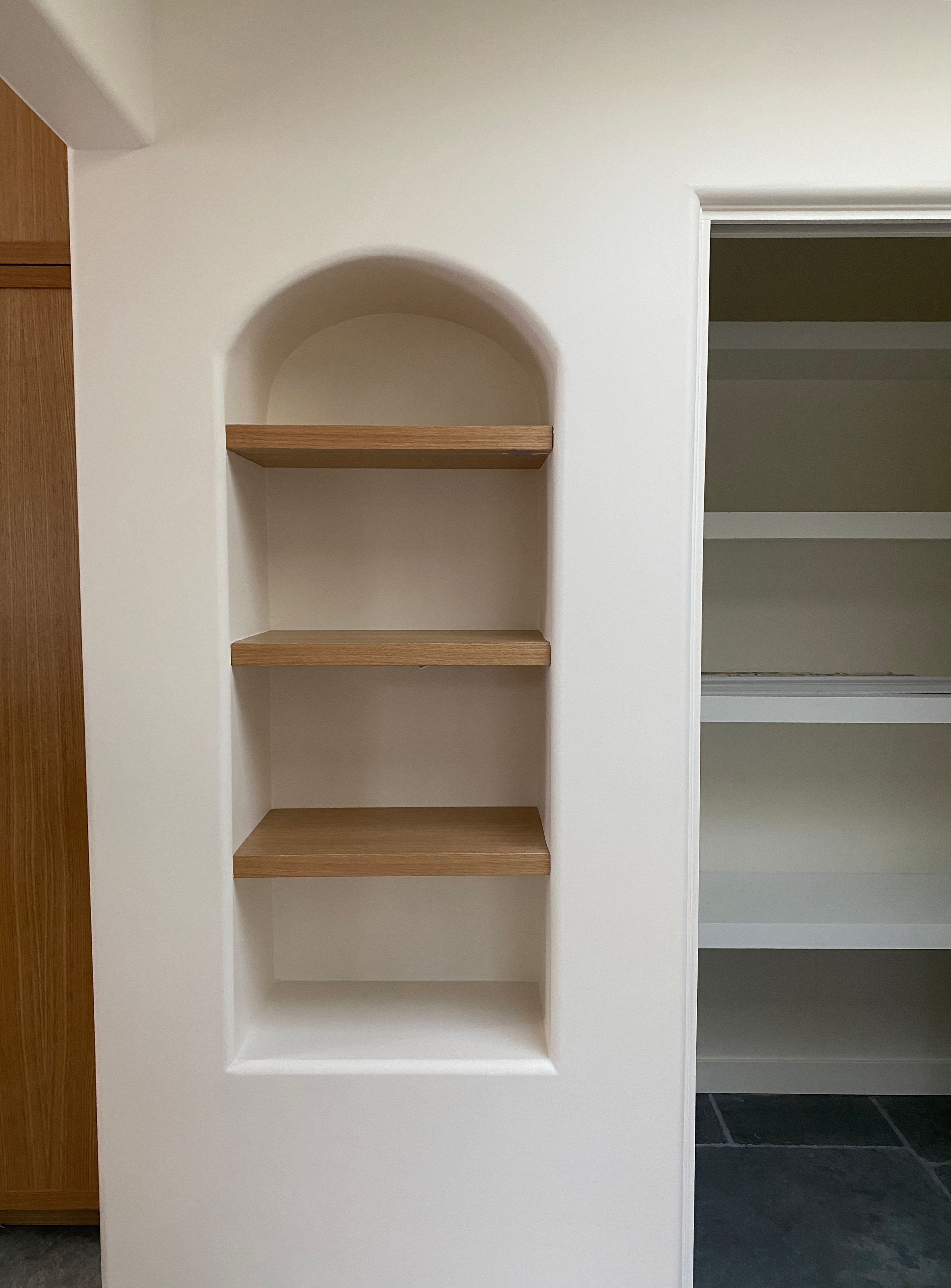 Arched wall niches and wood grain help soften and contrast against a clean tidy kitchen