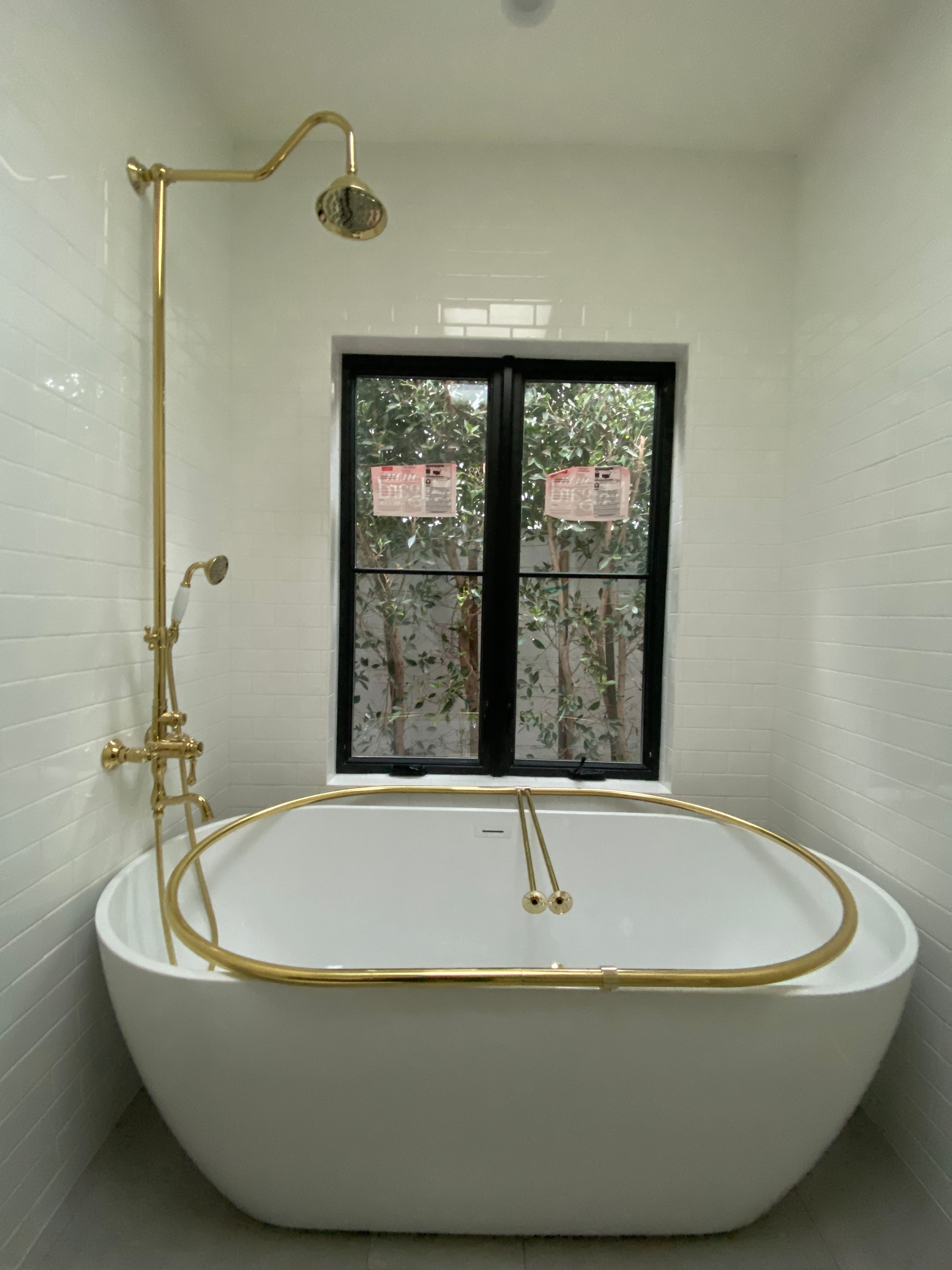 A free-standing soaking tub with a classic shower kit and oval curtain rod