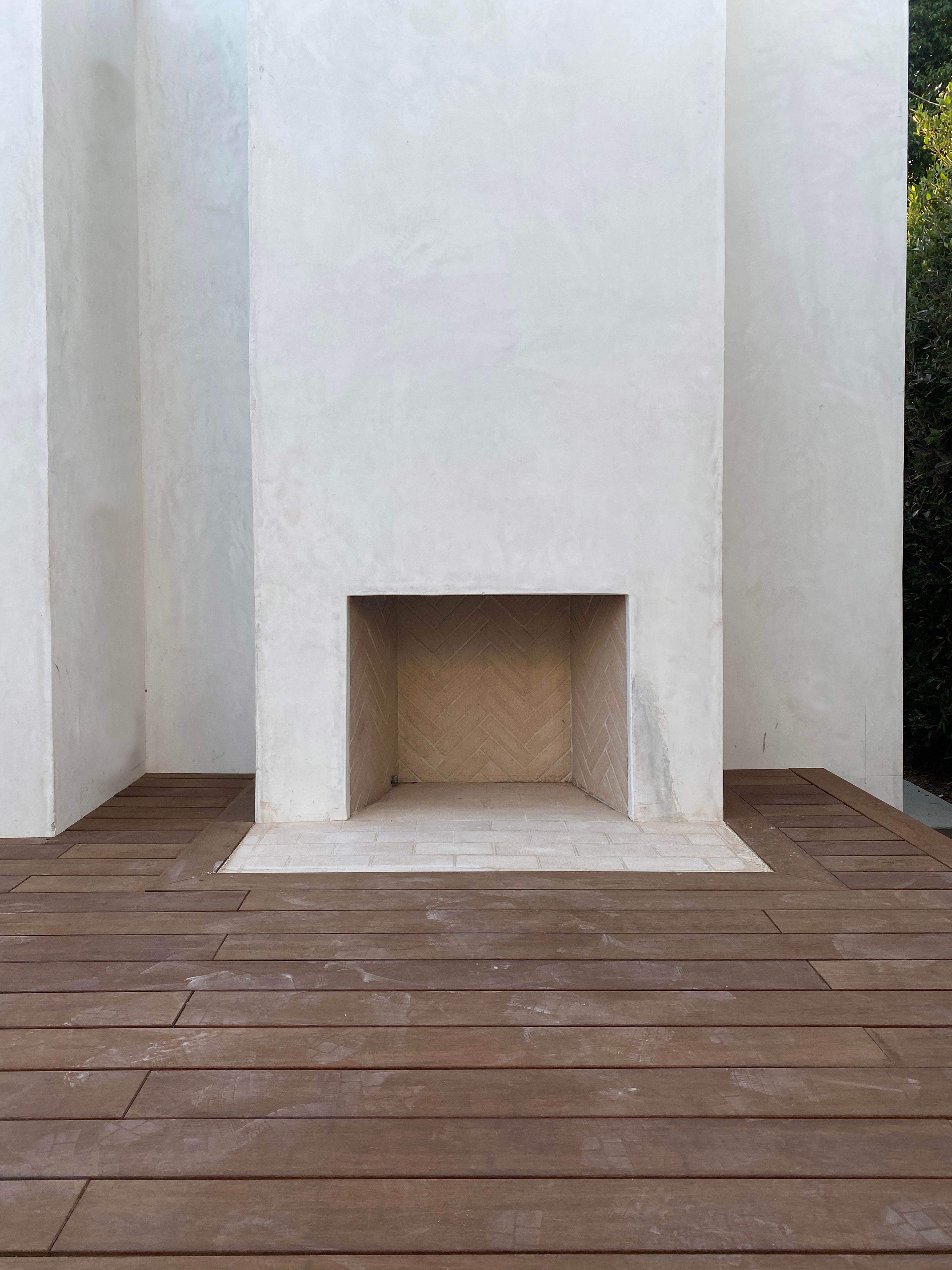 An outdoor fireplace clad in smooth stucco with a sustainable bamboo deck