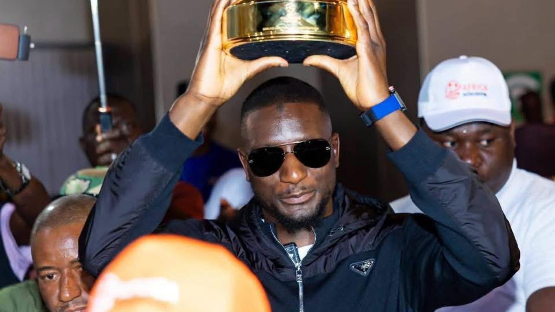 L'attaquant international guinéen Serhou Guirassy présente son trophée de meilleur buteur de la Ligue des Champions UEFA à son arrivée à l'aéroport de Conakry.