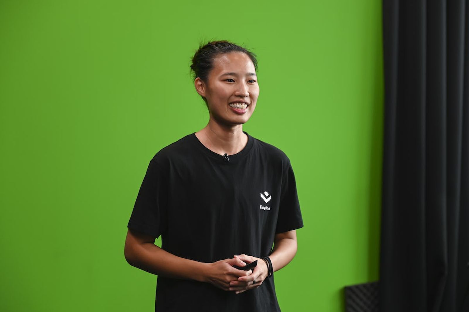 Image of Jiawen Ngeow Co-Founder of DayOne in front of green screen smiling 