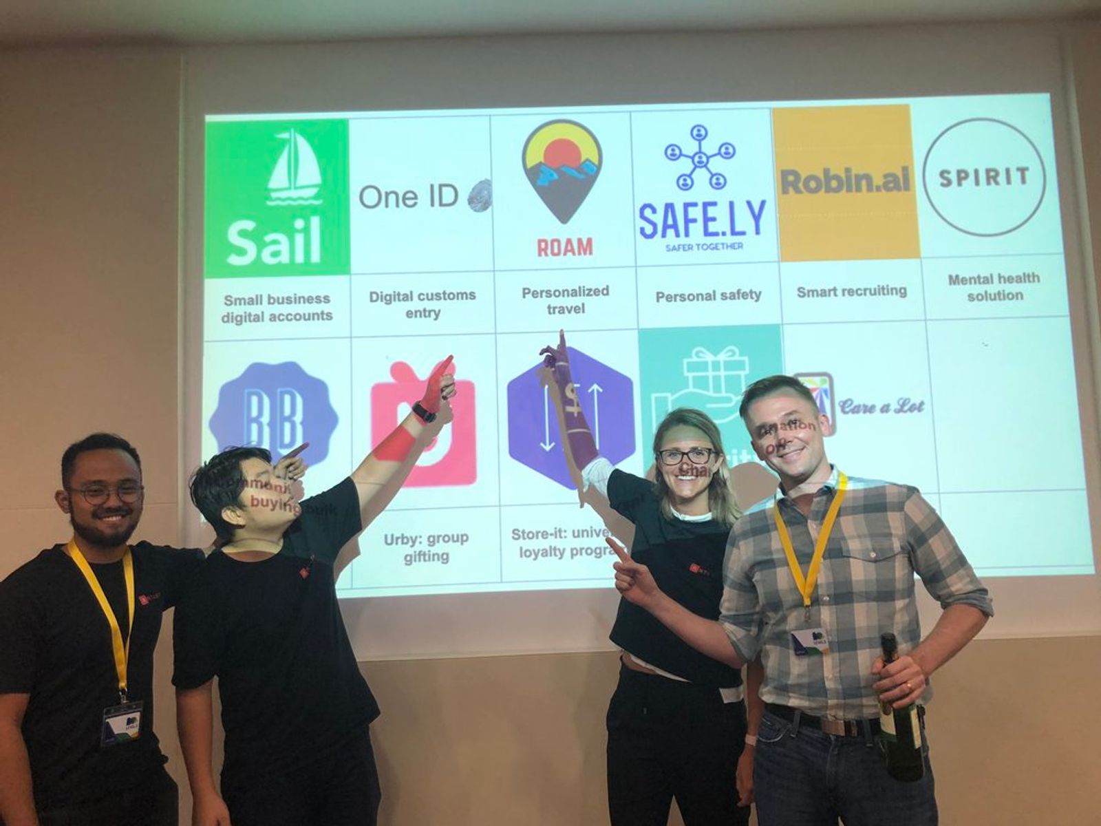 Team point at projection on board showing app-based platform for first Antler Cohort