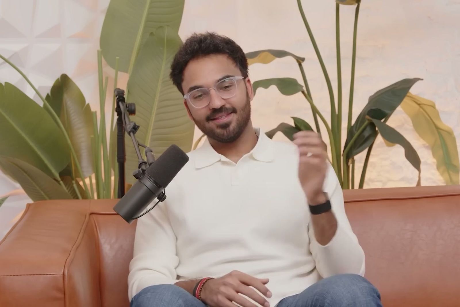 Shash Murarka, smiling and gesturing as he talks on a leather sofa on The Further, Faster Podcast