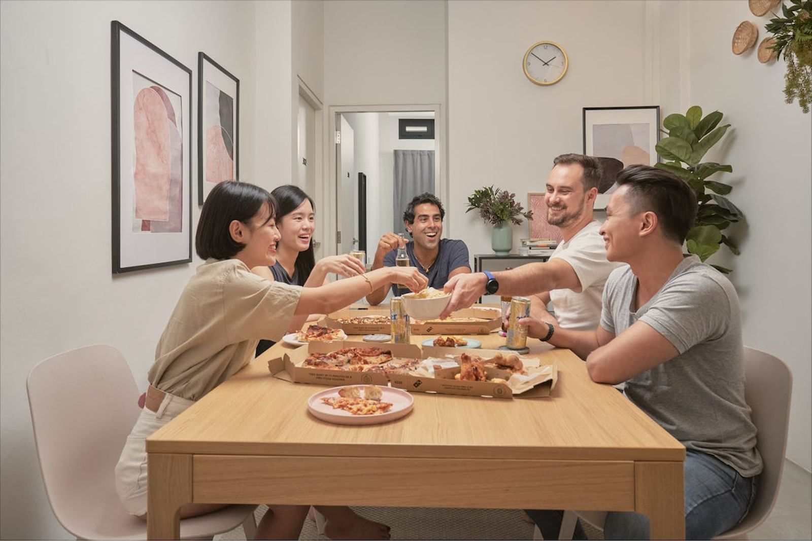 Group sitting around a table sharing pizza and smiling 