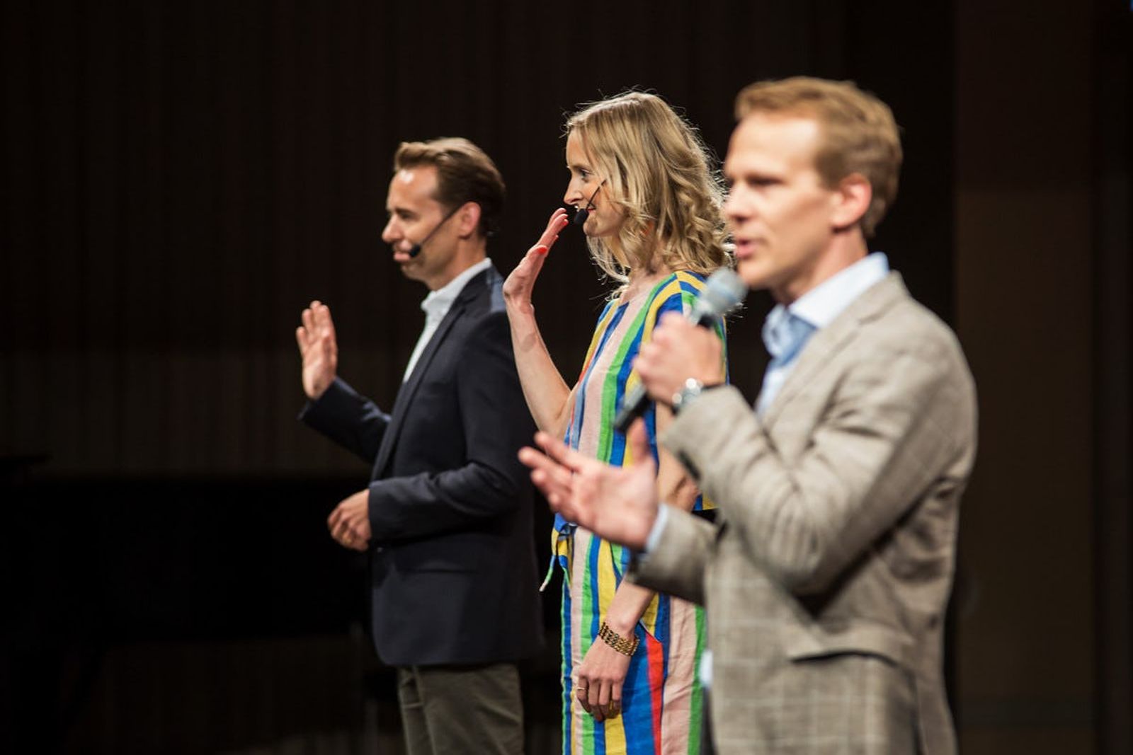 Three speakers greet the audience with one holding microphone at Stockholm's inaugural Demo Day