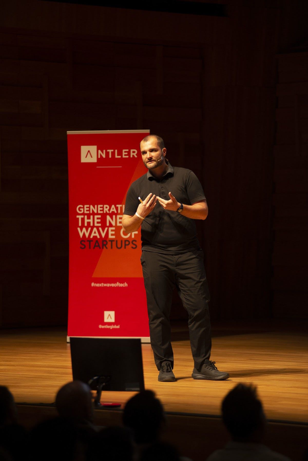 Sama representative presenting on stage at Singapore Demo Day with Antler sign in the background