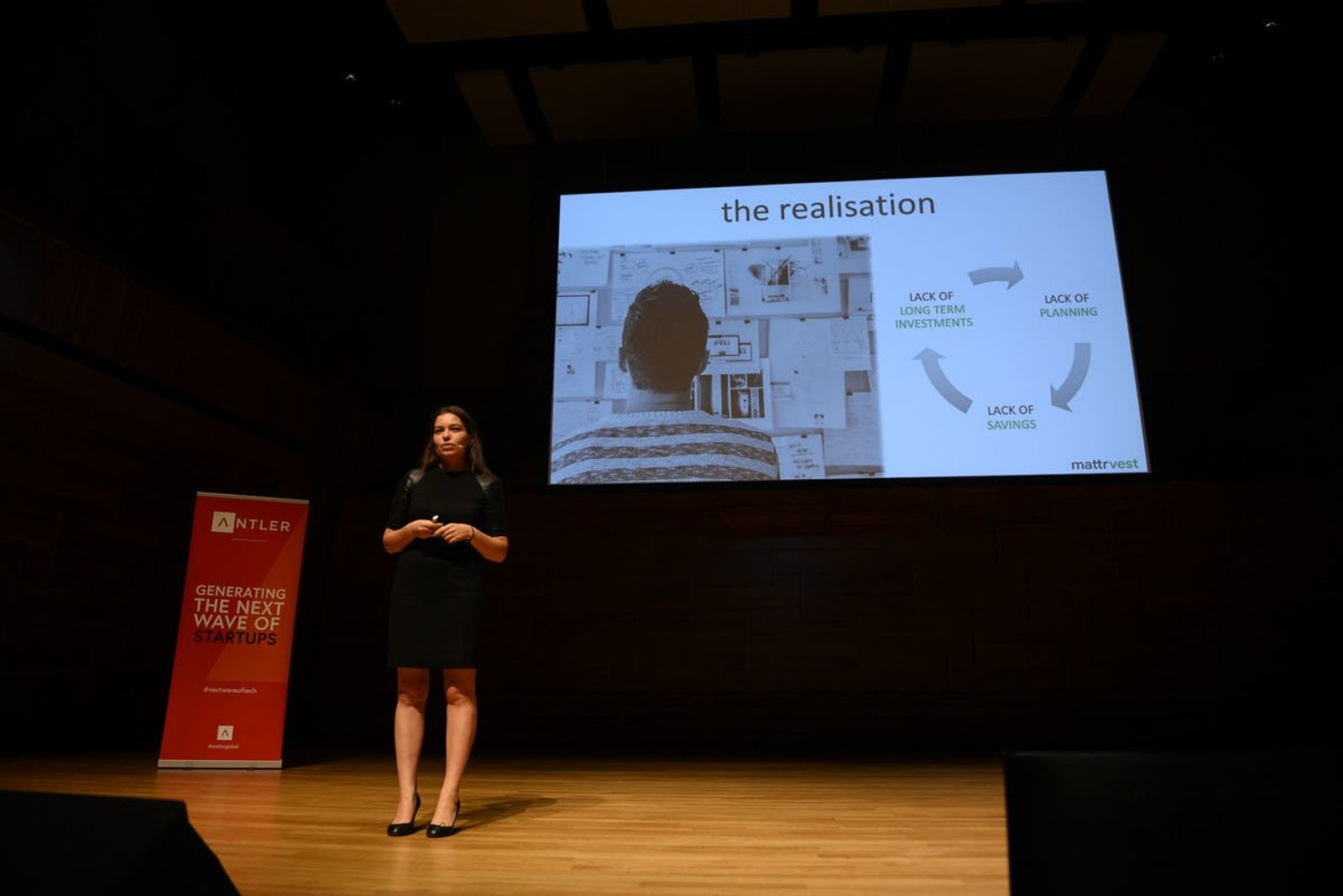 Mattrvest representative presenting on stage at Singapore Demo Day with Antler sign and presentation in the background  