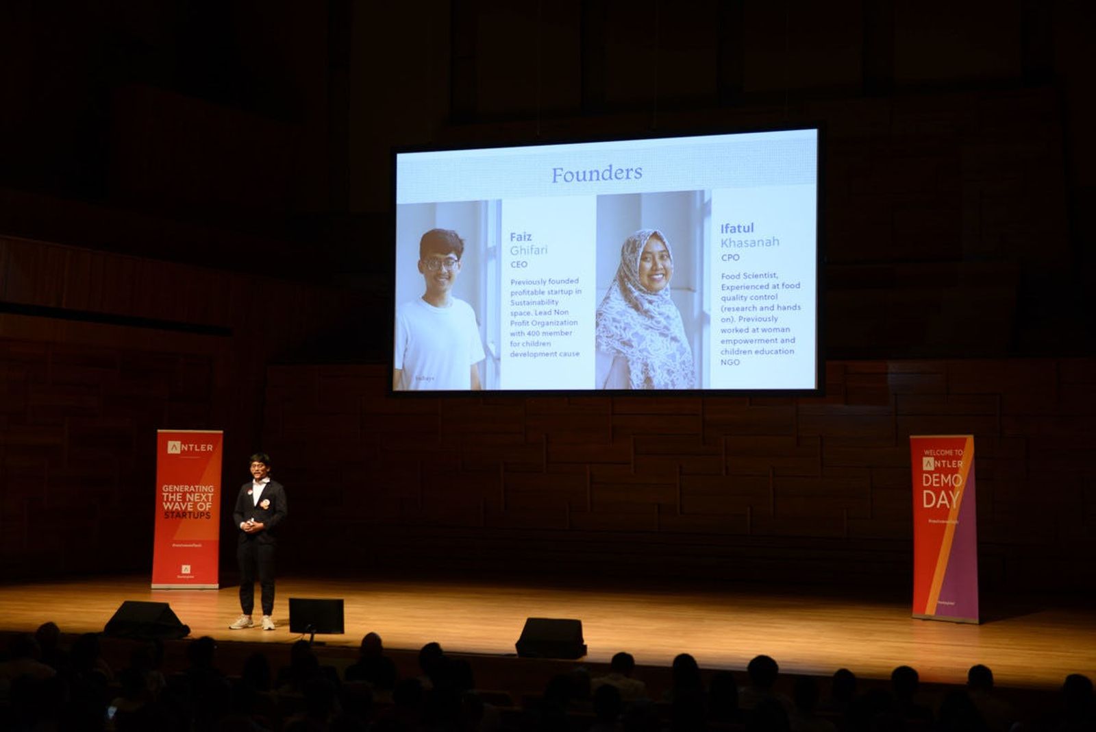 Audience watch Bubays representative presenting on stage at Singapore Demo Day with Antler signs and presentation in the background 
