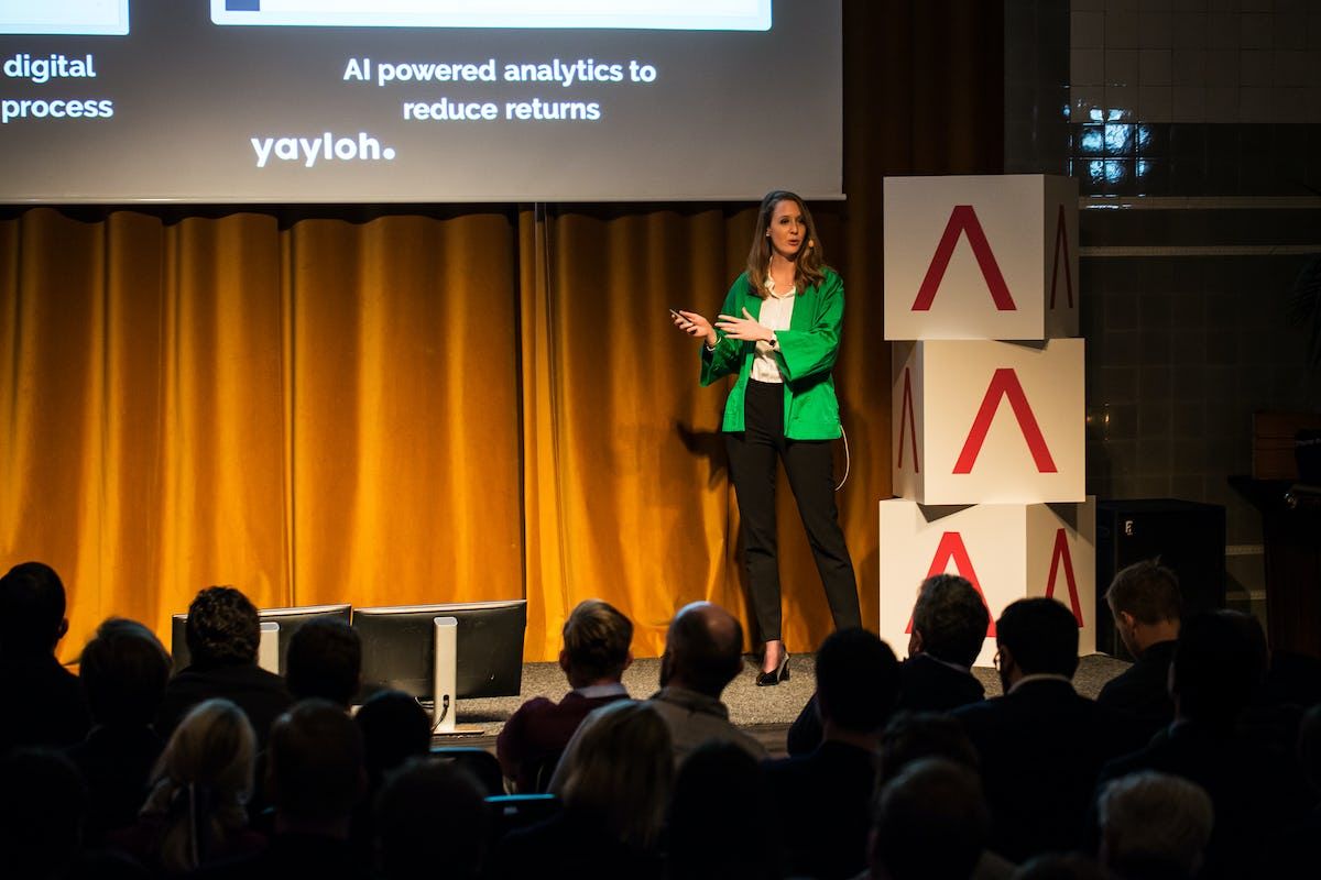 Audience watch antler representative provide a presentation next to antler logo boxes