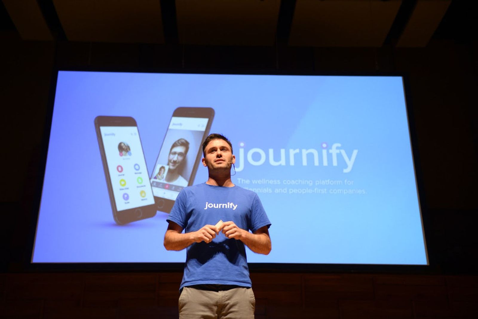 Journify representative presenting on stage at Singapore Demo Day with Journify presentation in the background