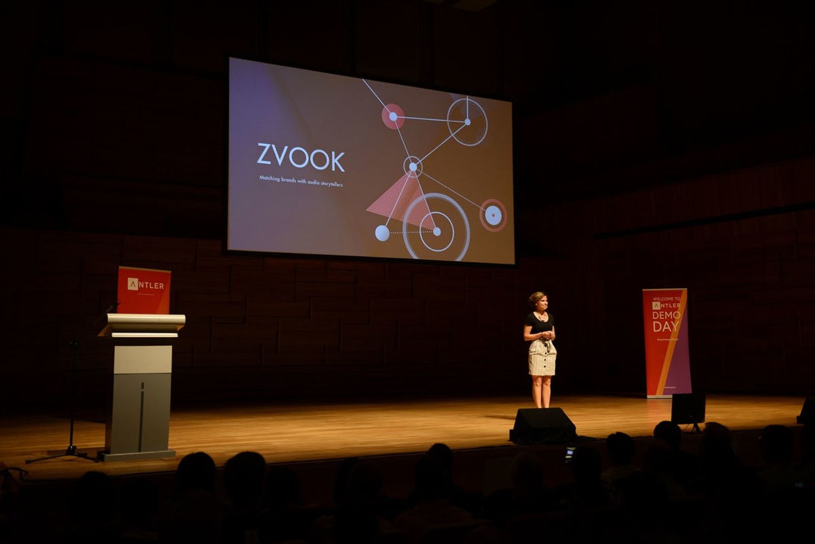 Audience watches Zvook representative presenting on stage at Singapore Demo Day with Antler signs in the background 