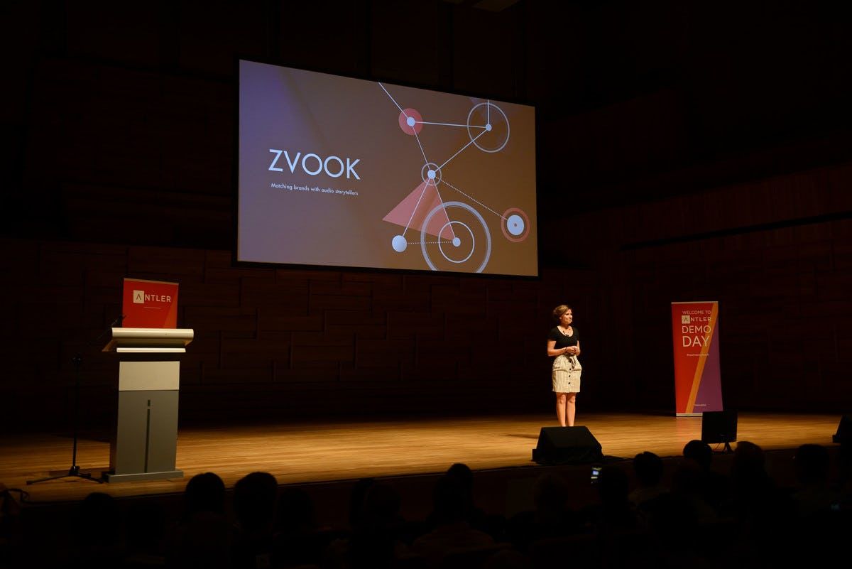 Audience watches Zvook representative presenting on stage at Singapore Demo Day with Antler signs in the background