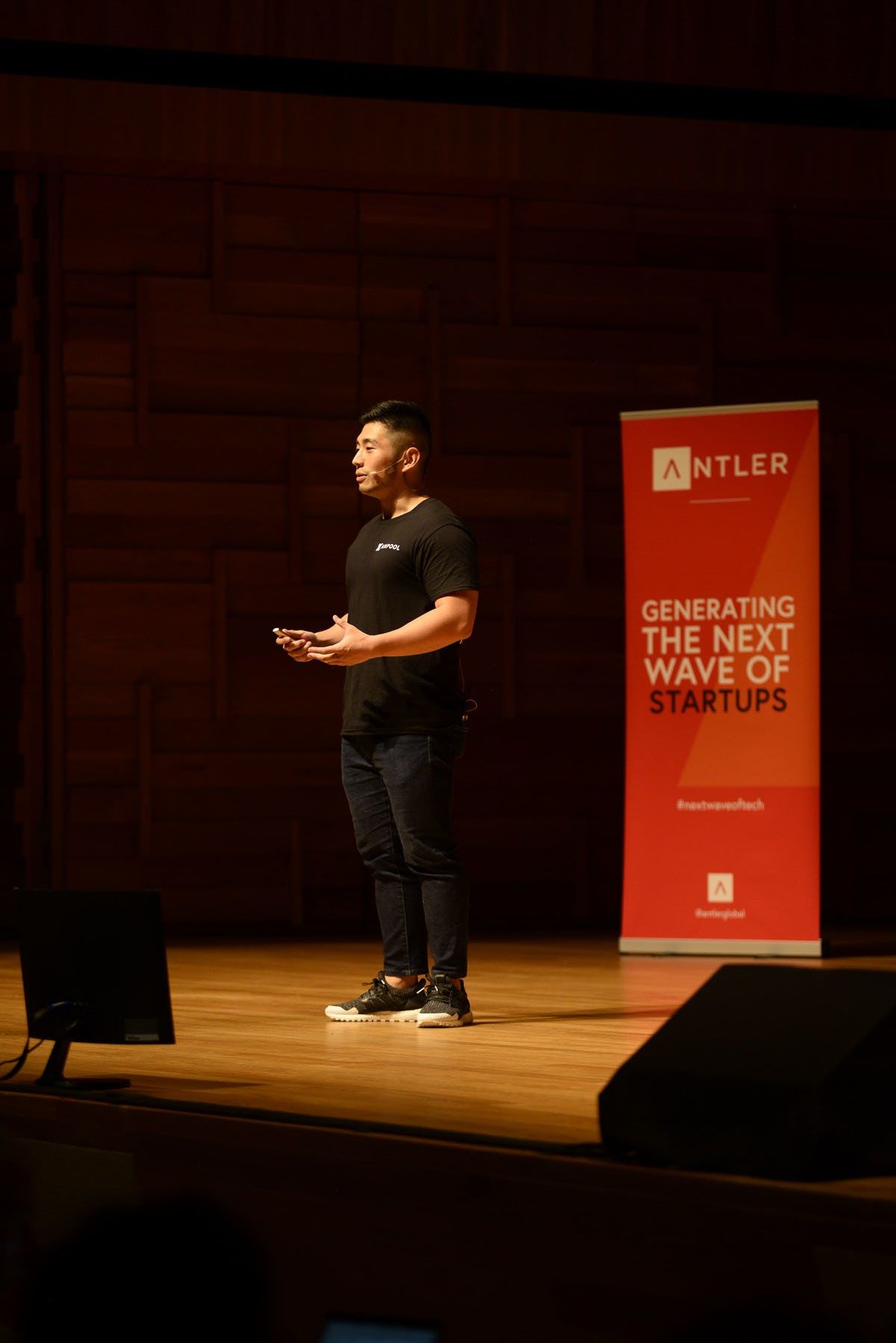 Xanpool representative presenting on stage at Singapore Demo Day with Antler sign in the background