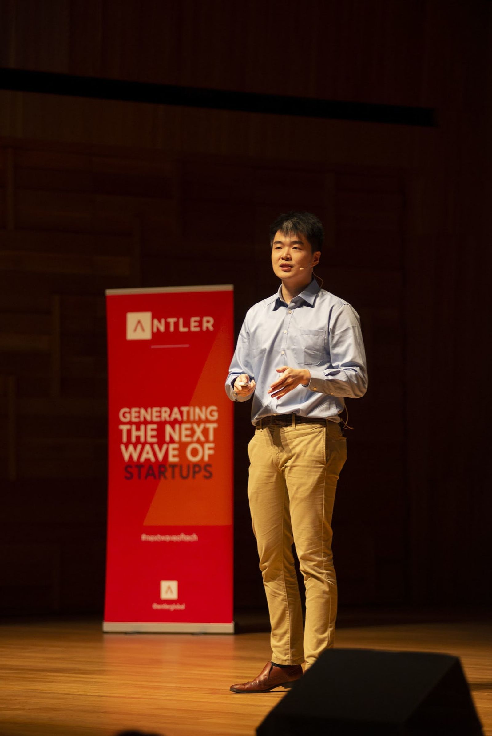 Hodlnaut representative presenting on stage at Singapore Demo Day with Antler sign in the background 
