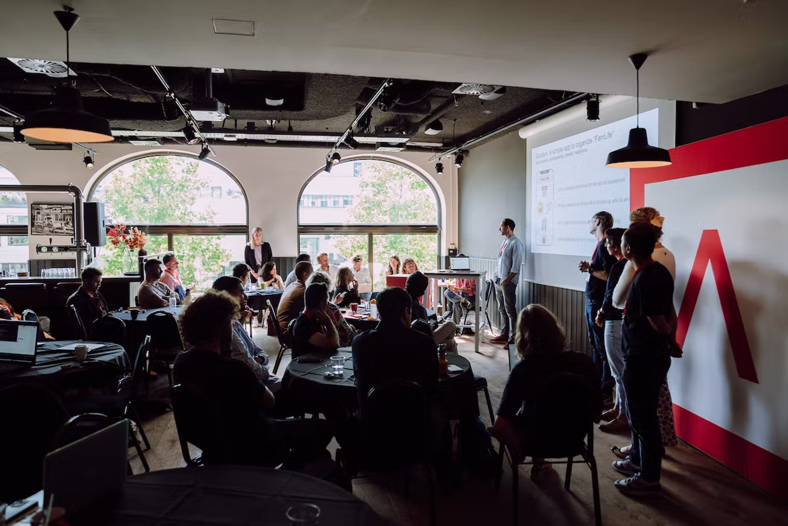 Sitting audience watches Antler presentation in Amsterdam with Antler logo in background