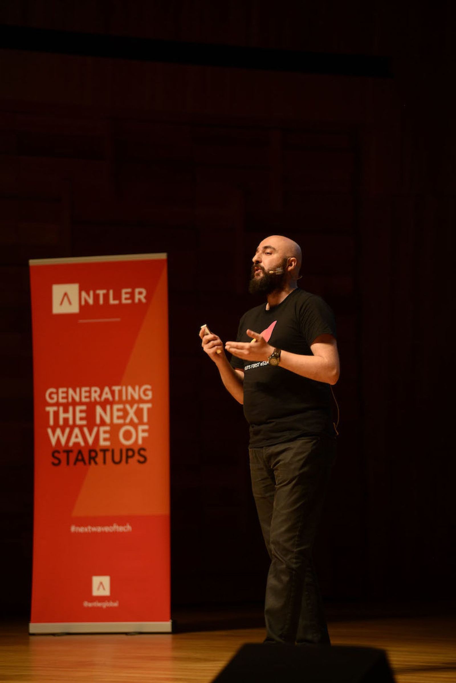 Airalo representative presenting on stage at Singapore Demo Day with Antler sign in the background 