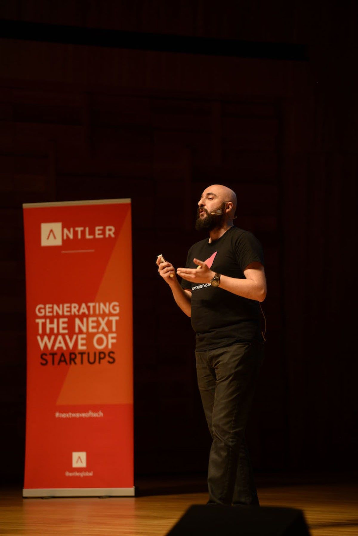 Airalo representative presenting on stage at Singapore Demo Day with Antler sign in the background