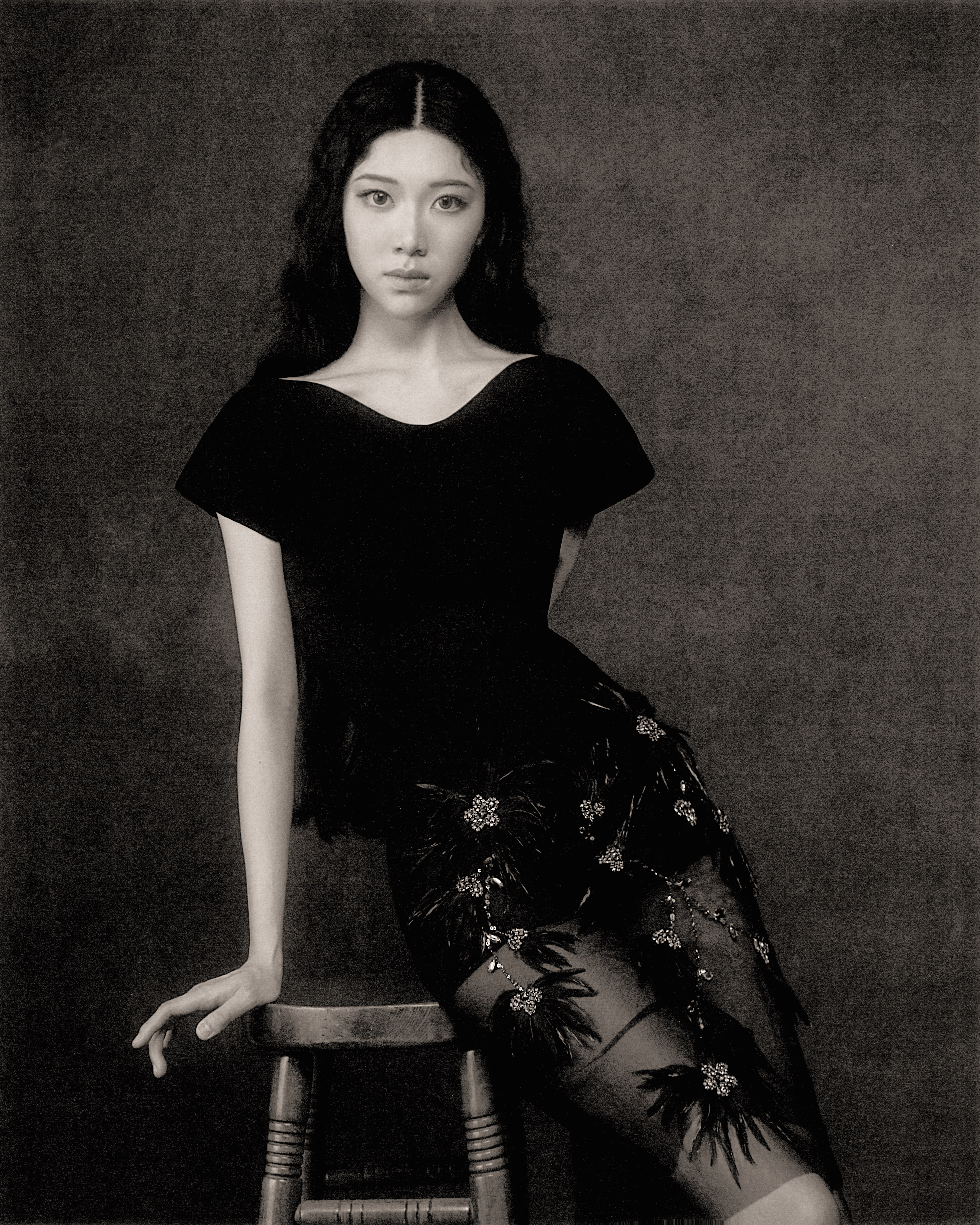 Sammi Chen seated in a black dress against a charcoal backdrop.