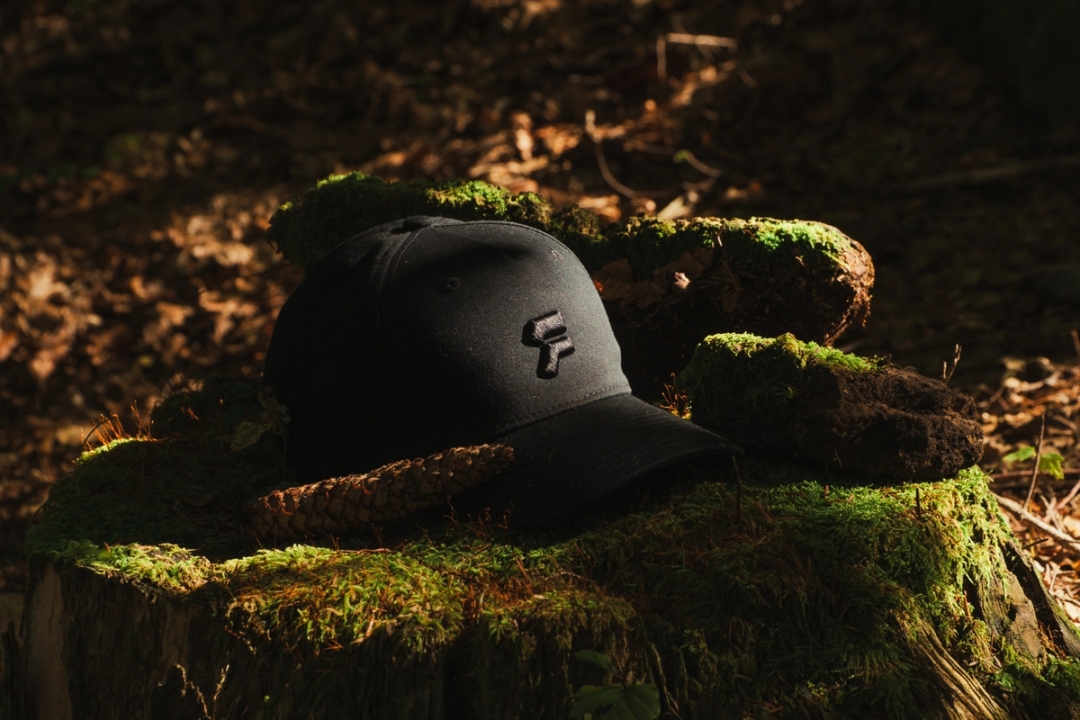 A Format-3 branded cap laying on a trunk in a forest