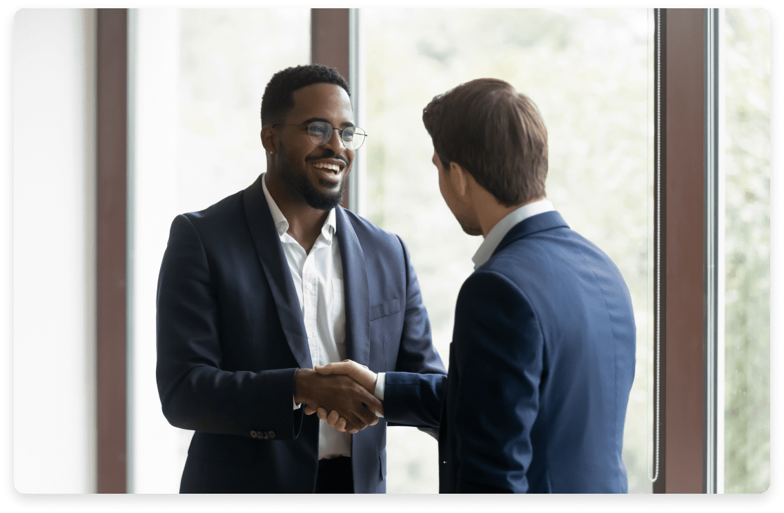 Two professionals in business attire shaking hands in a well-lit office, exemplifying the partnership and trust established through fractional CFO services for marketing companies.