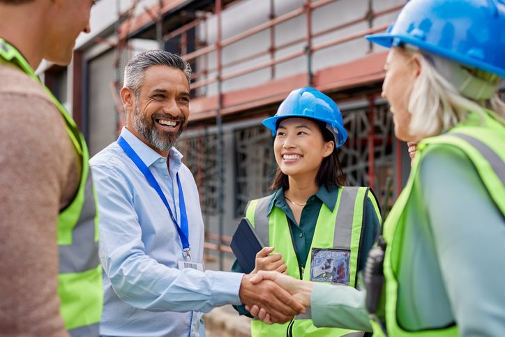 Smiling professional shaking hands with construction workers.