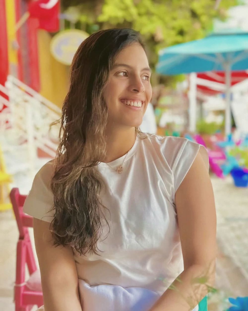 Aleja Carvajal, smiling, in a white T-shirt at a café table