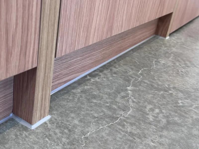 Silicone bead at a joinery-to-floor junction, cut in clean against the substrate