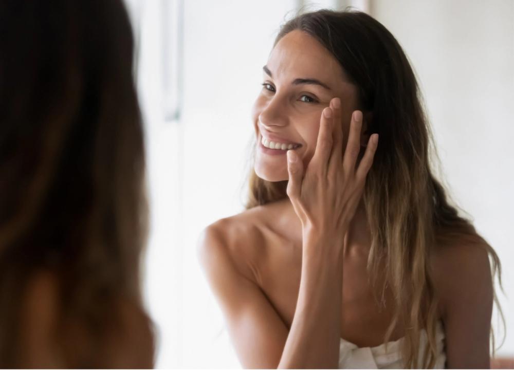 woman looking at her skin in a mirror