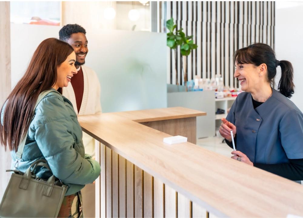 Couple smiling at receptionist in clinic