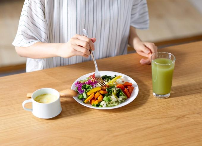 person eating a colorful salad and drinking juice