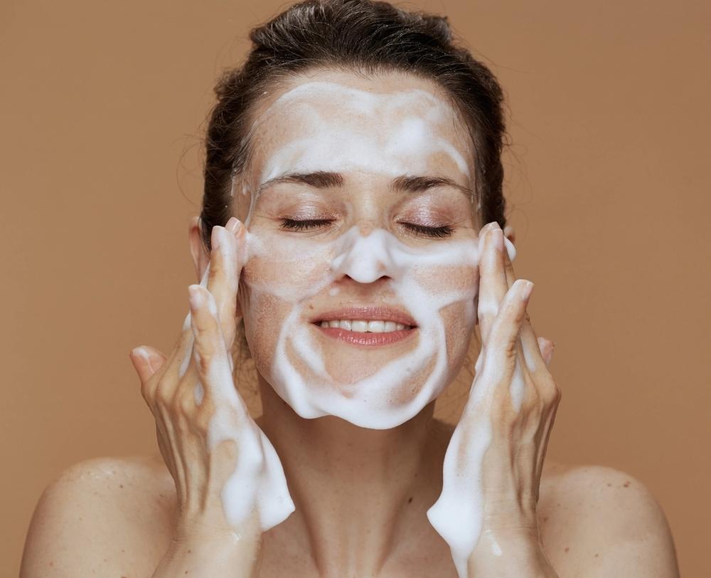 woman washing her face with a foaming cleanser