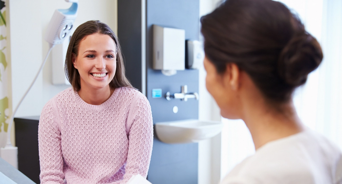 a happy woman in a pink shirt consulting a doctor at the office
